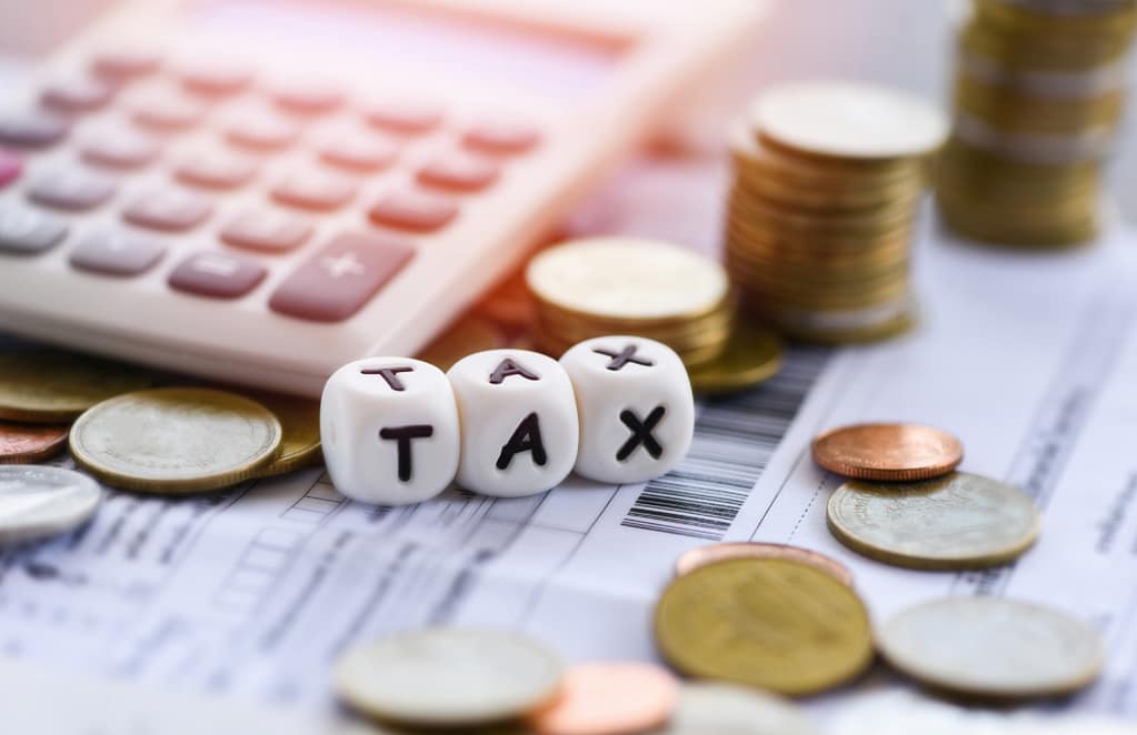 Dice spelling TAX with coins and calculators